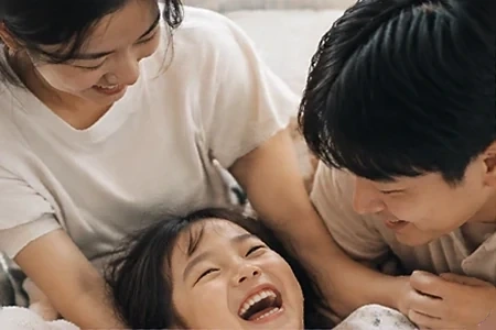 엄마 아빠와 함께 누워 활짝 웃는 아이